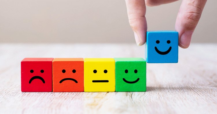Faces expressing emotions depicted on coloured blocks. A hand is lifting up the smiling block